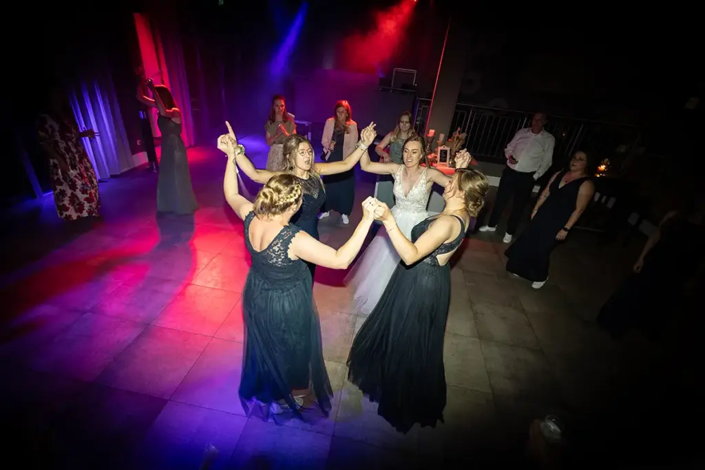 Ausgelassene Stimmung auf der Tanzfläche: Hochzeitsgäste feiern bei bunter Partybeleuchtung