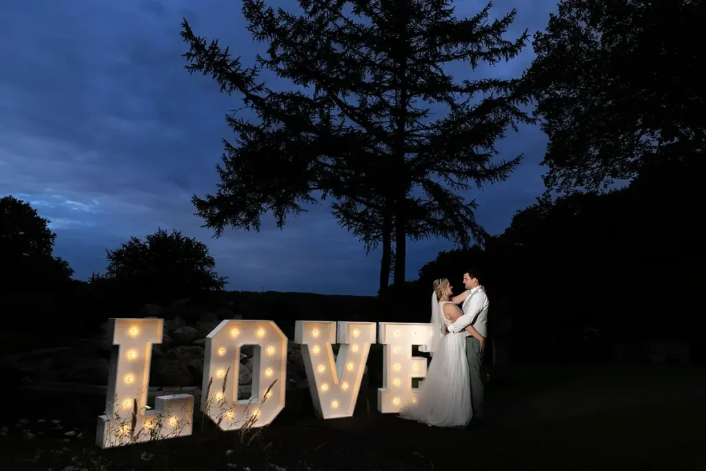 Brautpaar mit großen LOVE Buchstaben zur blauen Stunde