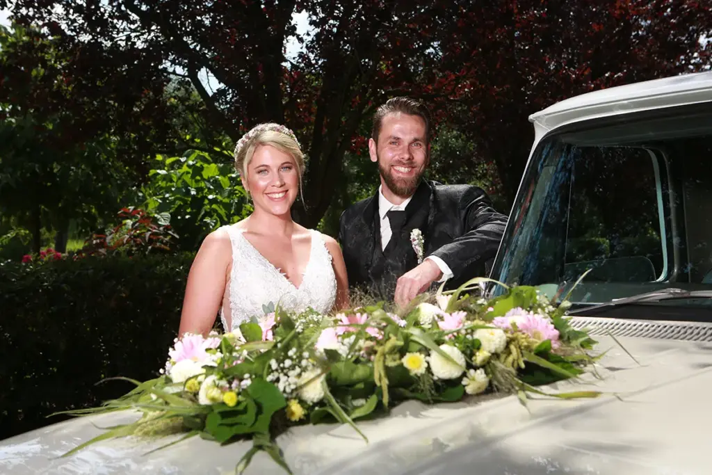 Großaufnahme des Brautpaares vor dem Oldtimer Brautwagen