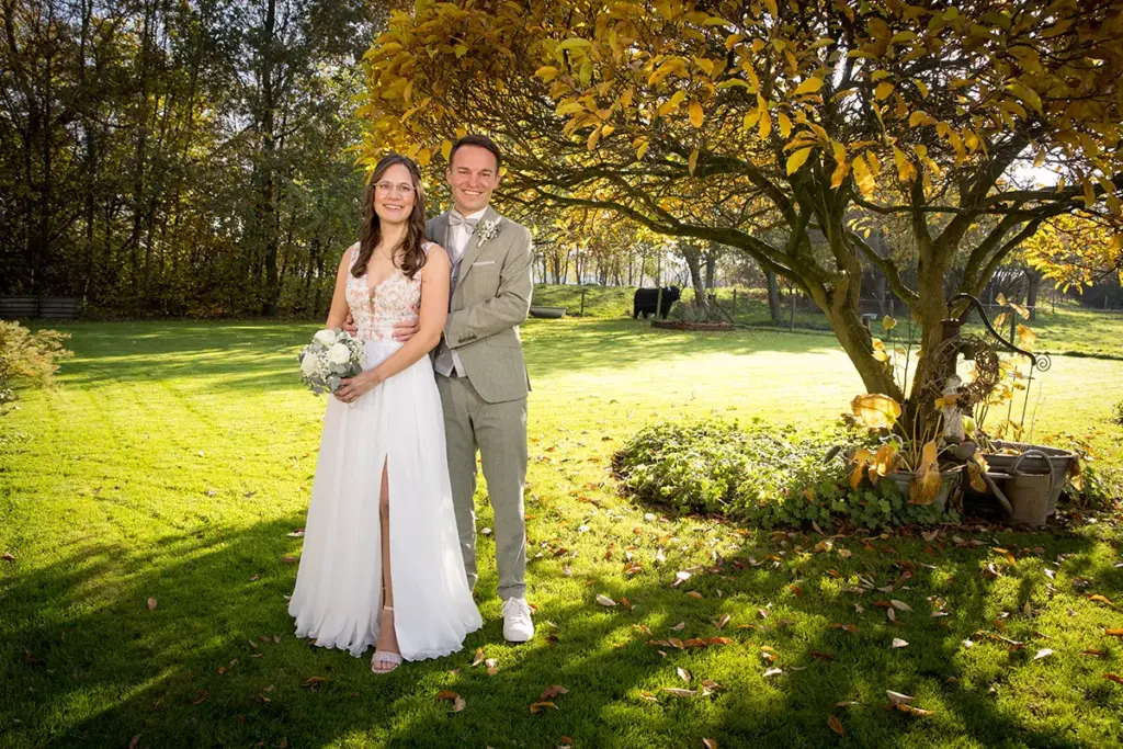 Portrait des Brautpaares unter einem Baum, im Gegenlicht geblitzt