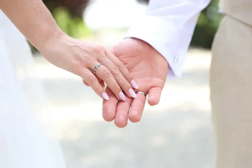 Ein Brautpaar berührt sich zärtlich an den Händen