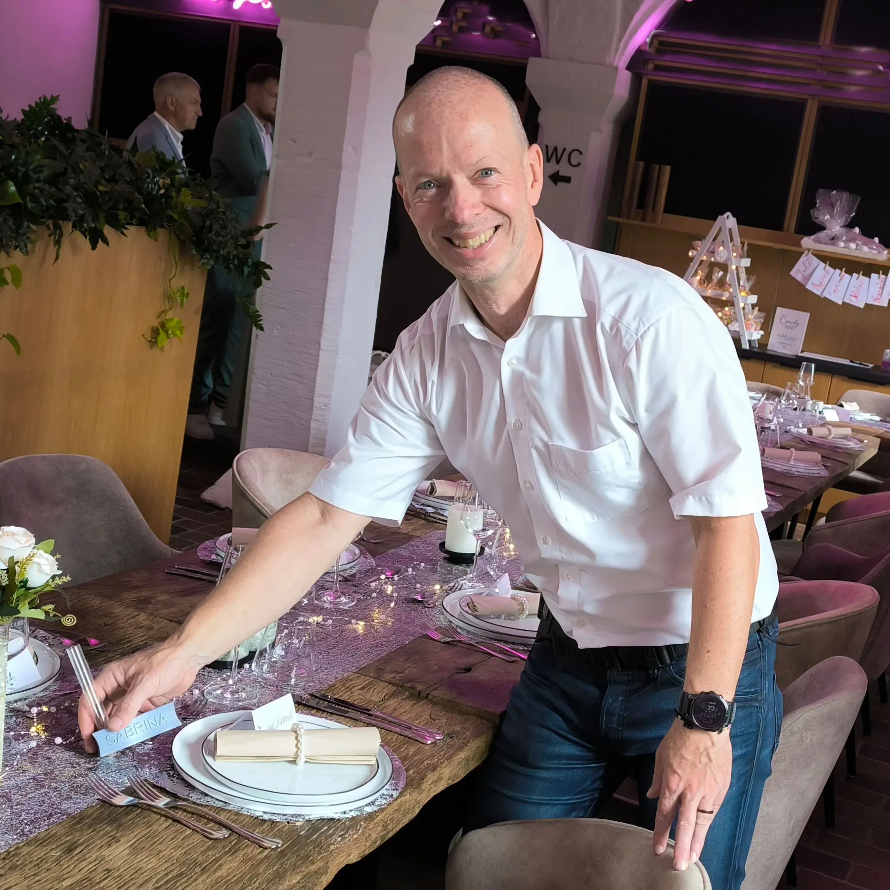 Thorsten Gramke platziert personalisiertes Tischschild auf Hochzeitstafel